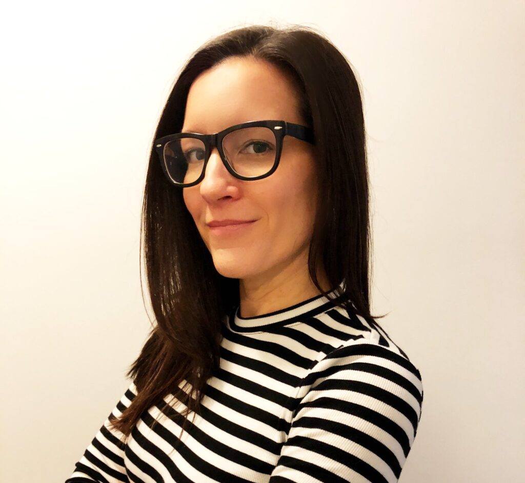Picture of Karen Costa (white woman wearing glasses in black and white striped shirt crossing her arms)