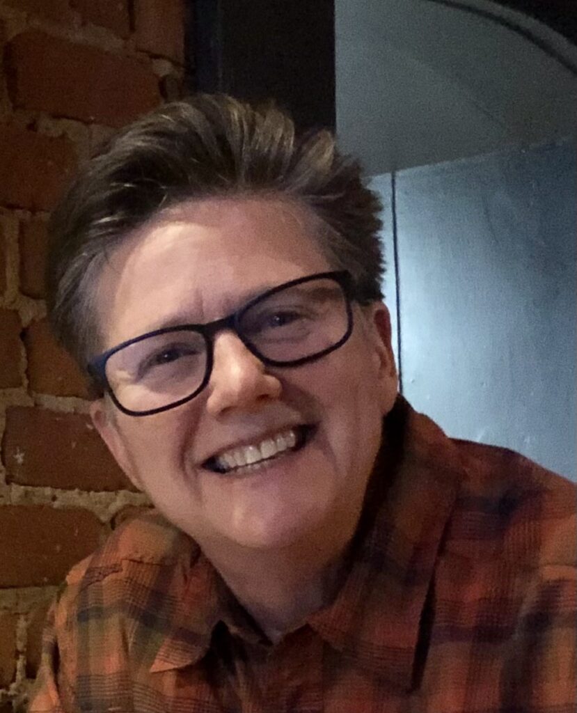 Photo of Karen Cangialosi, a white woman with glasses, short brown hair, and a huge smile.